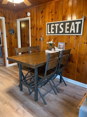 Enjoy meals in this dining area with a wooden table and chairs, surrounded by a warm atmosphere.