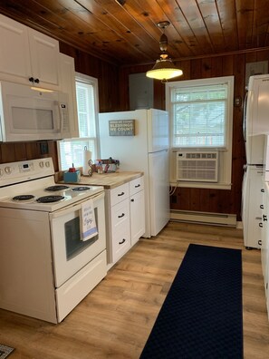 Compact kitchen with a stove, microwave, refrigerator, and kitchen island with sink and storage.