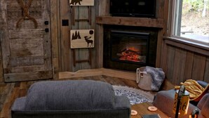 Una habitación acogedora con chimenea, paredes de madera, televisión y decoración con motivos de animales.