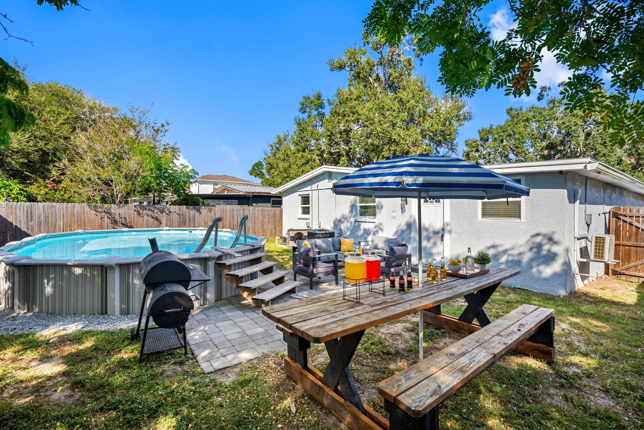 Un jardin avec un jacuzzi, un barbecue, une table de pique-nique et un espace salon extérieur.
