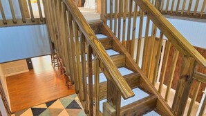 A wooden staircase with a geometric patterned rug and a small potted plant at the bottom. - Centrally Located in Heart of Sister Lakes, Michigan (Dowagiac)