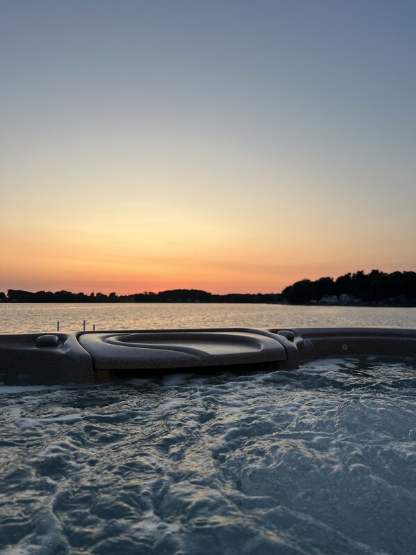 A hot tub with a view of a sunset over a body of water.