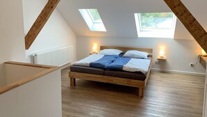A bedroom with a sloped ceiling, skylights, a wooden bed, bedside lamps, and a radiator. - Wangerooge by Interhome (Westerholt)