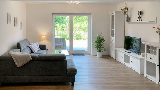 A modern living room with a grey sofa, a TV, and a white cabinet. - Wangerooge by Interhome (Westerholt)