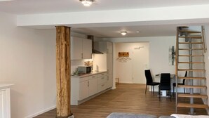 A modern living room with a grey sofa, a wooden column, a kitchen in the background, and a wooden staircase. - Wangerooge by Interhome (Westerholt)