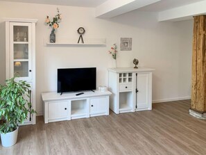 A living room with a flat-screen TV on a white cabinet, a potted plant, and a wooden accent wall. - Wangerooge by Interhome (Westerholt)