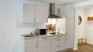 A modern kitchen with white cabinets, a stainless steel range hood, a microwave, and a sink. - Wangerooge by Interhome (Westerholt)