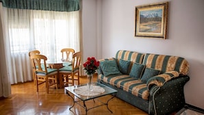 A living room with a striped sofa, wooden chairs, a glass coffee table, and a painting on the wall. - Modern apartment right in centre of Alicante Spain (Alicante)