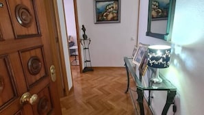 A hallway with a wooden door, a glass table with a lamp, and a painting on the wall. - Modern apartment right in centre of Alicante Spain (Alicante)