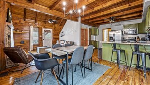 A rustic wooden interior with a dining area, kitchen, and a staircase leading to another level.