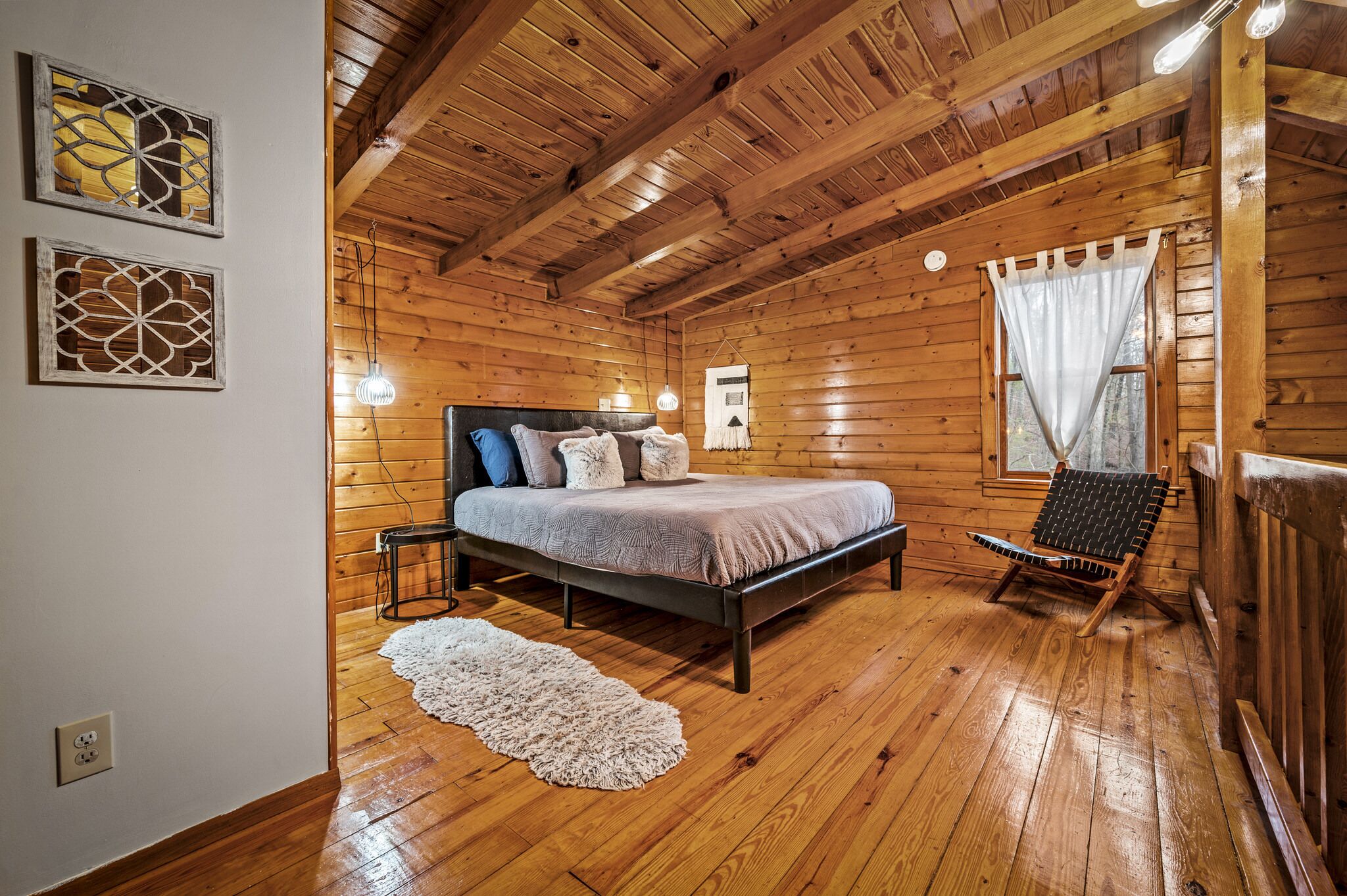 A wooden cabin bedroom with a bed, a chair, and a small table.