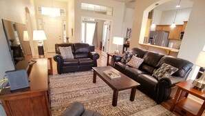 A spacious living room with a dark leather sofa, a wooden coffee table, and a patterned rug. - Beautiful Home in Golf Course Community - 3 Bedroom plus Den (Meridian)