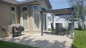 A covered patio area with a table and chairs, a grill, and a lawn. - Beautiful Home in Golf Course Community - 3 Bedroom plus Den (Meridian)