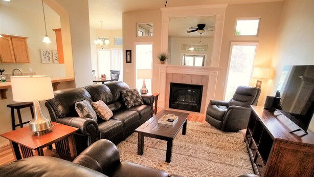 A living room with a fireplace, leather sofas, a coffee table, and a television. - Beautiful Home in Golf Course Community - 3 Bedroom plus Den (Meridian)