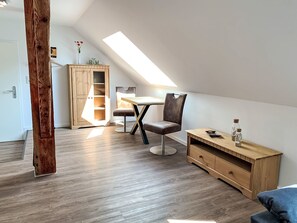 A modern loft bedroom with a sloped ceiling, a wooden desk, a chair, and a small bedside table.
