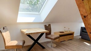 Camera da letto moderna tipo loft con finestra sul tetto, tavolo da pranzo in legno, divano e comò in legno.