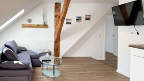 Un soggiorno moderno con un divano grigio, un tavolino in vetro e una parete d'accento in legno.