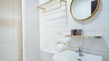 Un baño con inodoro, lavamanos y zona de ducha.