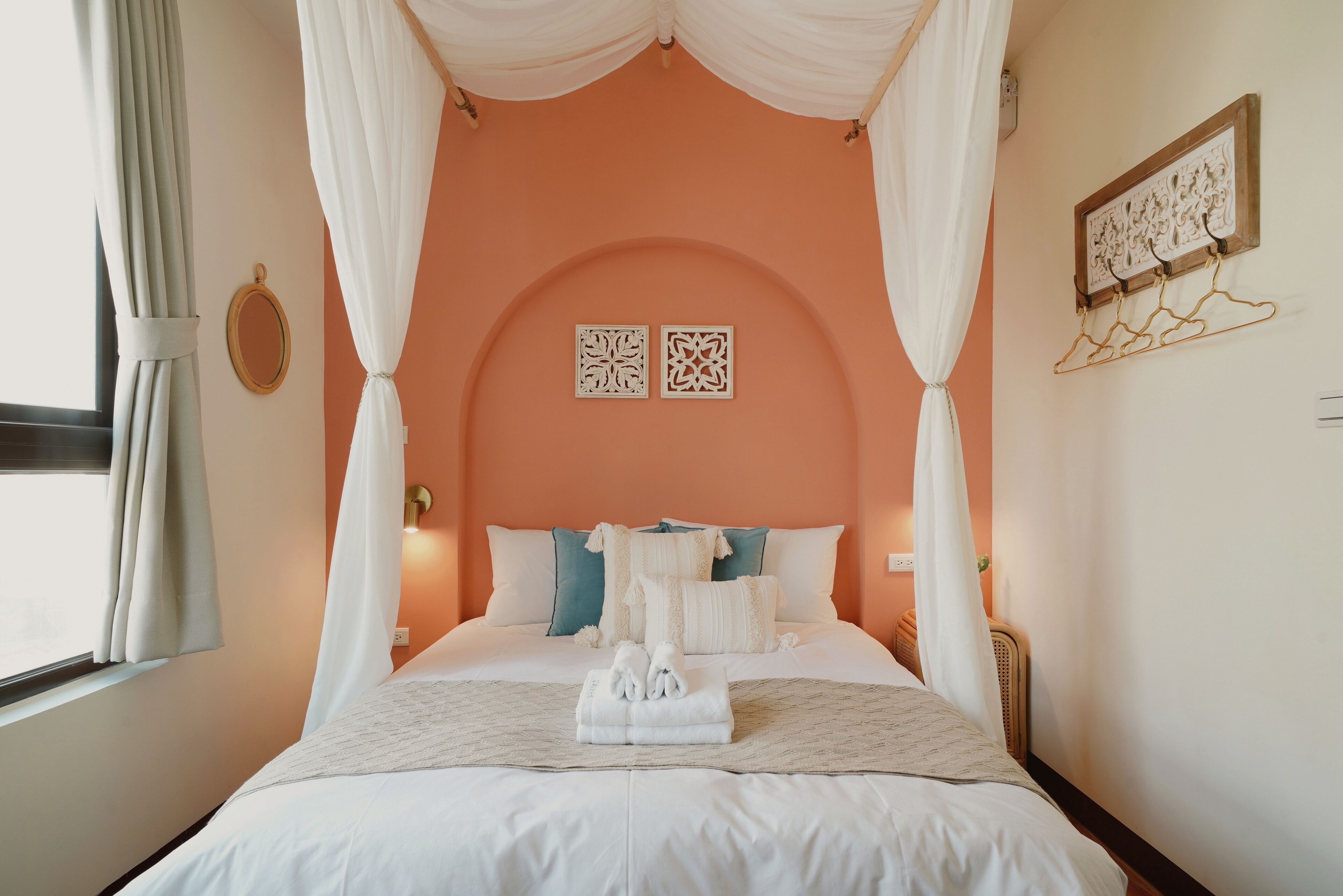 A bedroom with a four-poster canopy bed, white bedding, and a neatly folded towel on the bed.