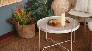 Une pièce chaleureuse avec une table ronde, des paniers en osier et une décoration murale en macramé.