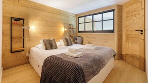 Un dormitorio con paneles de madera, una cama grande, una ventana y un armario de madera.