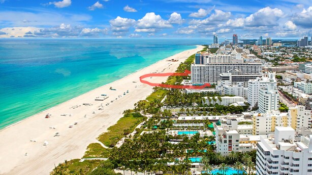 Un paysage urbain côtier avec une plage, des immeubles de grande hauteur et un ciel bleu dégagé.