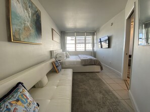 A modern bedroom with a large bed, a sofa, and a painting on the wall. - Beachfront apartment with Ocean View (Miami Beach)