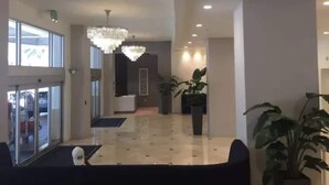 Un hall d’entrée spacieux, agrémenté d’un lustre, de plantes en pot et d’un comptoir d’accueil.