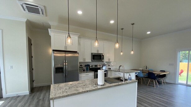 A modern kitchen with white cabinets, stainless steel appliances, and pendant lighting. - Have the Best of Both: Quick Access to Downtown Brevard & Pisgah Forest. (Brevard)
