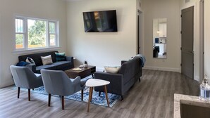 A modern living room with a sofa, chairs, a coffee table, and a TV. - Have the Best of Both: Quick Access to Downtown Brevard & Pisgah Forest. (Brevard)