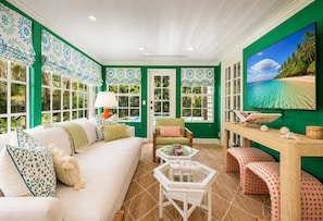 Una habitación con pared verde, techo blanco y un ventanal grande. Hay un sofá blanco, una mesita y una silla.