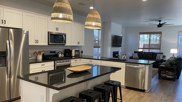A modern kitchen with white cabinets, stainless steel appliances, a large island with stools, and pendant lighting. - 5 Bedroom, 5 Minutes from Downtown (Flagstaff)