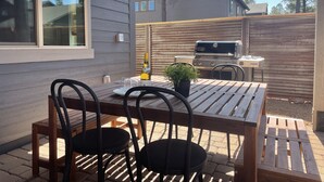 An outdoor patio with a wooden table and chairs, a bottle of wine, and a grill. - 5 Bedroom, 5 Minutes from Downtown (Flagstaff)