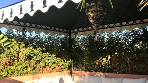 Zona d'estar a l'aire lliure amb sofà, taula i cistella decorativa.