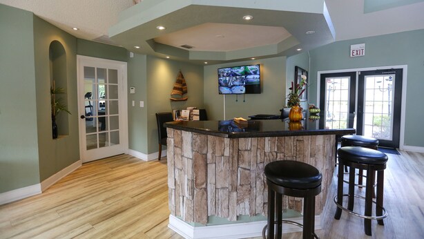A kitchen with a stone island, bar stools, a TV, and a door leading to another room. - ✪KING BED LARGE VILLA✪ Close to Disney & Outlets! (Kissimmee)