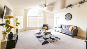 A living room with a ceiling fan, a sofa, a coffee table, and a TV on a stand. - ✪KING BED LARGE VILLA✪ Close to Disney & Outlets! (Kissimmee)