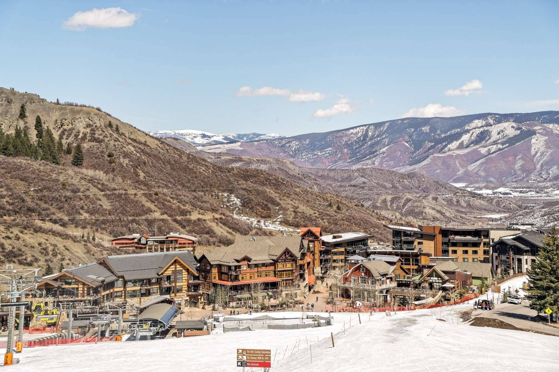 Un centro de esquí con varias cabañas, remontes y un paisaje cubierto de nieve.