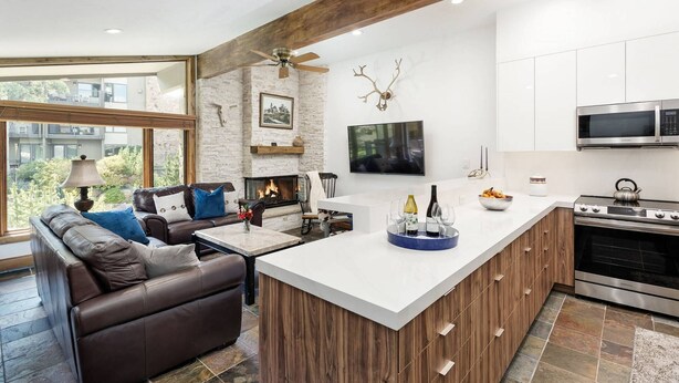 Eine moderne Küche mit einer zentralen Kochinsel, einem Kamin und einem Essbereich mit einer Couch.