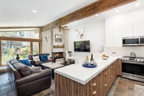 Una cocina moderna con una isla grande, una chimenea y un área de comedor con sofá y mesa.