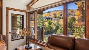 Ein Zimmer mit großem Fenster und Blick auf einen Skigebiet und Herbstlaub.