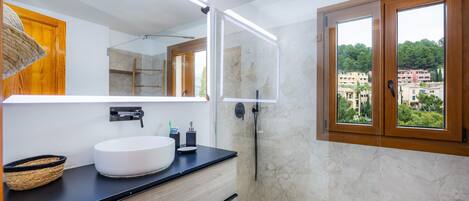 A modern bathroom with a large mirror, a white sink, and a shower.