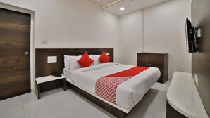 A modern hotel room with a large bed, a bedside table, a wardrobe, and a TV mounted on the wall. - Hotel Maan Palace (Ahmedabad)