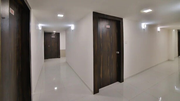 A hallway with white tiled floors and dark wooden doors, each marked with a number. - Hotel Maan Palace (Ahmedabad)
