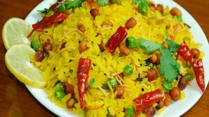 A plate of yellow rice with peas, red chilies, and peanuts, garnished with lemon slices and cilantro. - Hotel Maan Palace (Ahmedabad)
