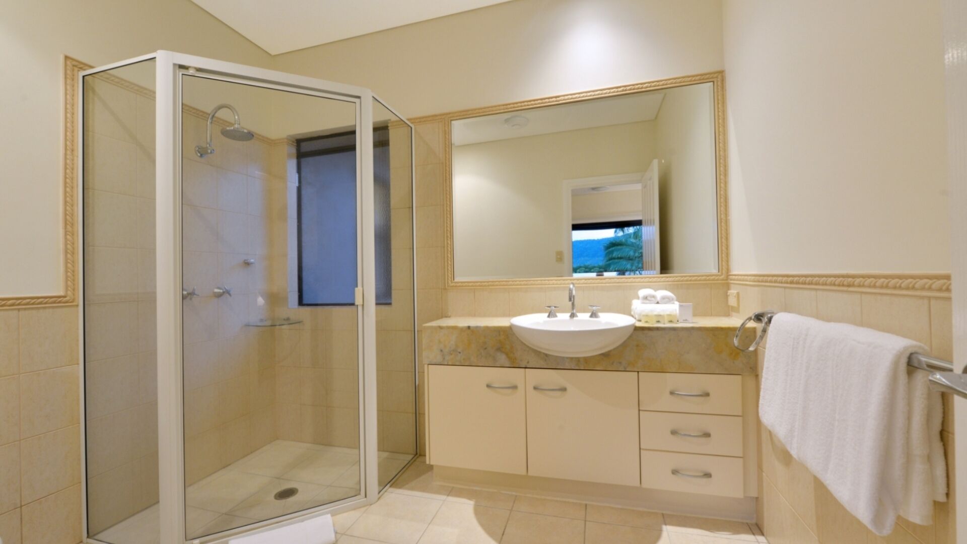 A modern bathroom with a glass-enclosed shower, a sink with a mirror above, and a towel rack.