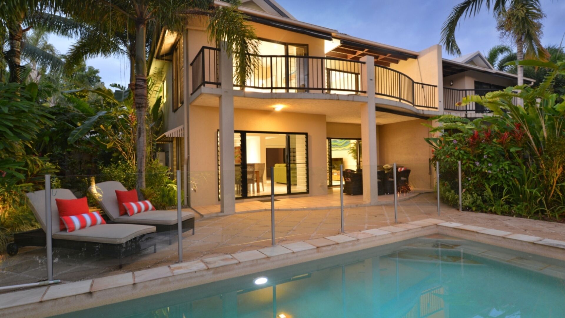 A two-story house with a balcony, a swimming pool, and outdoor furniture.