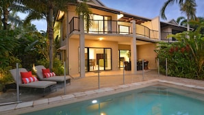 Une maison à deux étages dotée d’un balcon, d’une piscine et de mobilier d’extérieur.