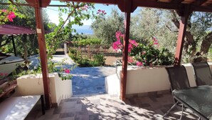 A covered outdoor area with a stone patio, a table, chairs, and a boat. - Cozy vacation apartment Panorama1 (Eretria)