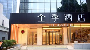A hotel entrance with a revolving door, a sign with Chinese characters, and a glass facade. - Ji Hotel (Lianyungang)