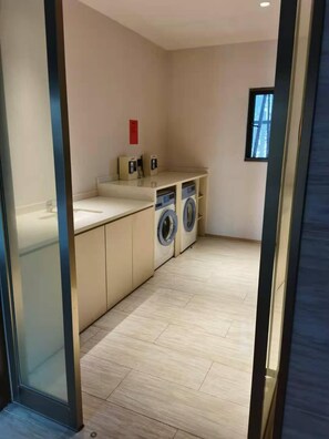 Una cocina moderna con lavadora integrada, un ventanal pequeño y una encimera con lavamanos.